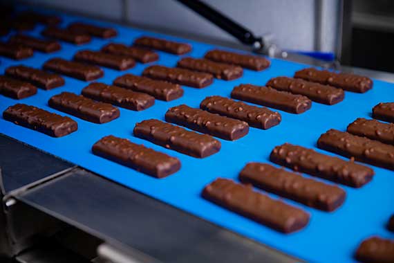 A batch of HFSS compliant, chocolate protein bars running along a factory belt.